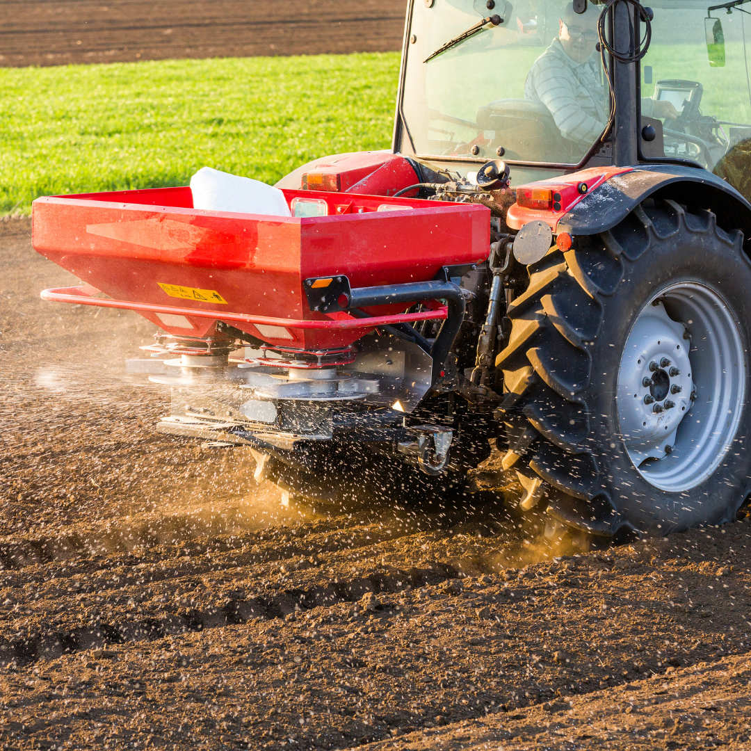 Red tractor spreading fertilizer